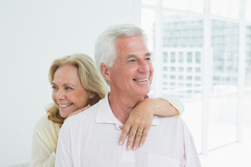Happy senior woman embracing man from behind