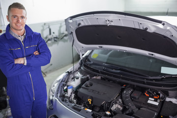 Smiling mechanic next to a car