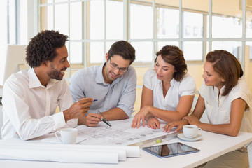 Colleagues working on blueprints in office