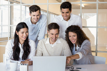 Casual business team having a meeting using laptop