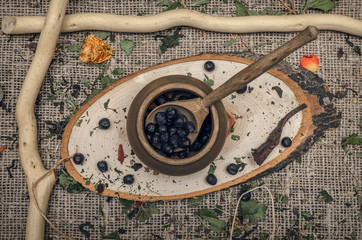 Herbal medicine concept. Phytotherapy. Wild black berry in the pot on wooden table background.