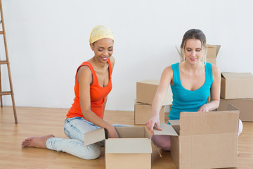 Happy friends unwrapping boxes in a new house