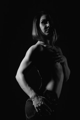 Young female model with muscular body poses on a dark background. black and white