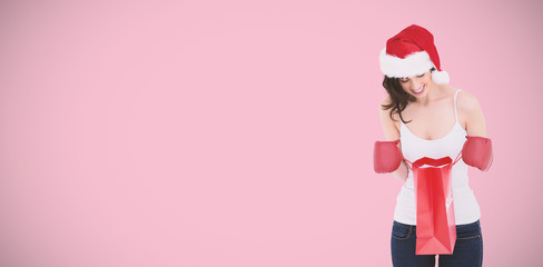 Happy brunette in boxing gloves looking in shopping bag against pink background