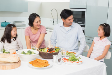 Obraz na płótnie Canvas Cheerful family of four enjoying healthy meal in kitchen