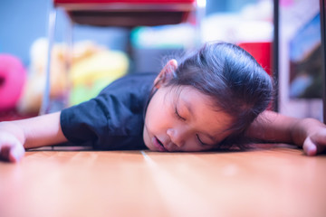 Girl sleeping on floor; tired children falling asleep crawling on hardwood floor at home.