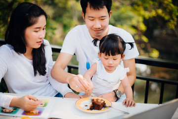 Happy family spending time at home and eating cake and playing computer; Family with mother, father, daughter.