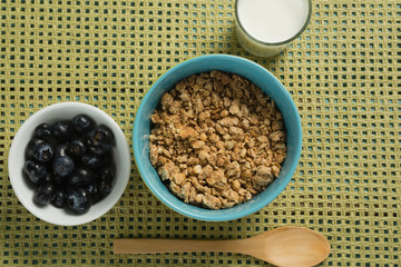 Bowl of cereals and blueberries with glass of yogurt for breakfast