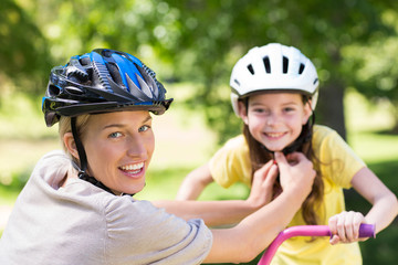 Mother attaching her daughters cycling helmet 