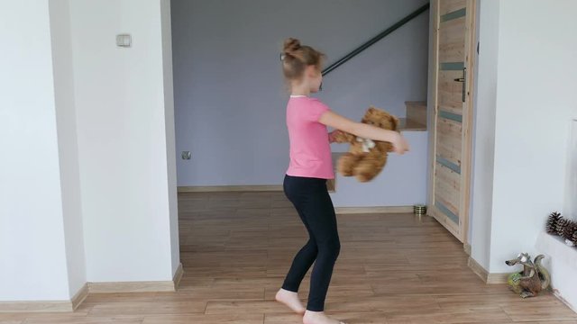 Happy, young girl is dancing with teddy bear.
