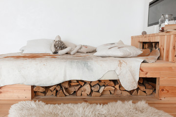 Fototapeta na wymiar Modern country house interior with wooden bed, firewood, fireplace