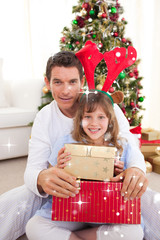 Composite image of Portrait of a father and his daughter holding Christmas presents with snow falling