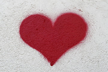 Coeur rouge peint sur un mur crème granuleux