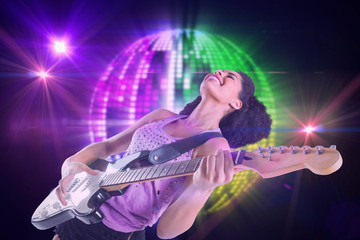 Pretty girl playing guitar against digitally generated cool disco ball design 
