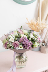 Obraz na płótnie Canvas White and lilac bouquet of beautiful flowers on wooden table. Floristry concept. Spring colors. the work of the florist at a flower shop. Vertical photo