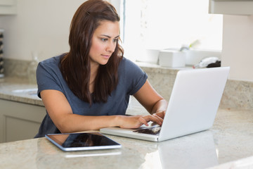 Fototapeta na wymiar Woman using laptop next to the tablet pc
