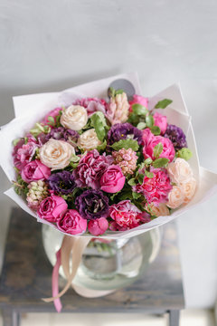purple and pink bouquet of beautiful flowers on wooden table. Floristry concept. Spring colors. the work of the florist at a flower shop. Vertical photo
