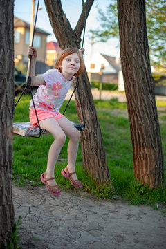 A girl is sitting on a swing, on a playground