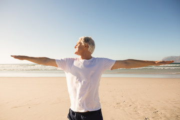 Senior man practicing yoga at beach