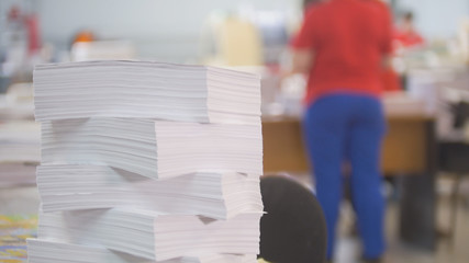 Paper stack in front of worker in the typography