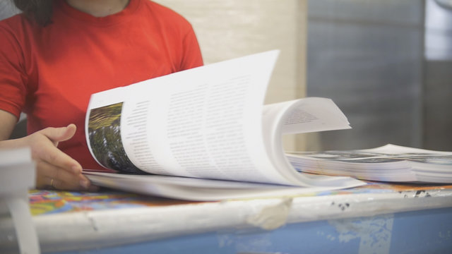 Hands of female worker in typography turning printed pages