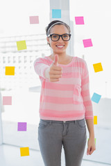 Smiling woman standing in her creative office giving thumb up