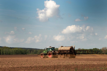 Fototapeta premium traktor mit tank und düngemaschine auf dem Feld