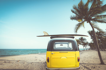 Arrière de voiture d& 39 époque garée sur la plage tropicale (bord de mer) avec une planche de surf sur le toit - Voyage de loisirs en été. effet de couleur rétro