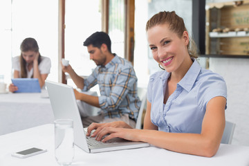 Fototapeta na wymiar Smiling woman using laptop in coffee shop