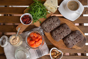 Rye bread sandwich with cream cheese, smoked salmon, arugula, on rustic wooden background, top view. Healthy delicious snack, breakfast or appetizer
