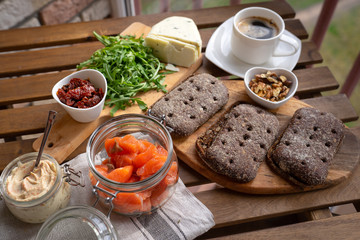 Rye bread sandwich with cream cheese, smoked salmon, arugula, on rustic wooden background, top view. Healthy delicious snack, breakfast or appetizer