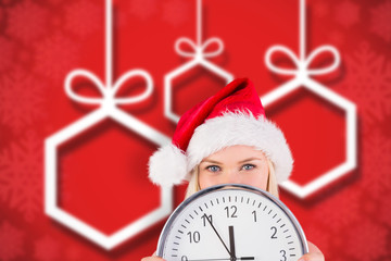 Festive blonde holding a clock against blurred christmas background