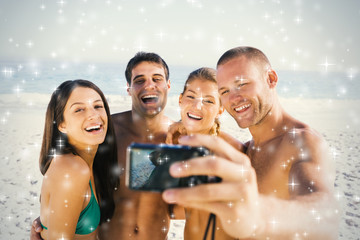 Cheerful friends taking pictures of themselves against snow