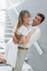 Loving young man carrying woman at home