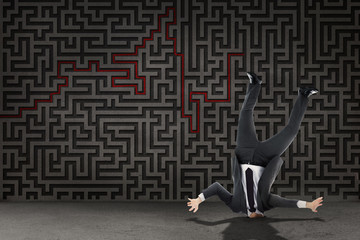 Businessman burying his head against grey maze