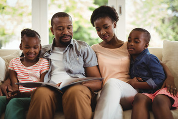 Parents and kids sitting together on sofa with photo album