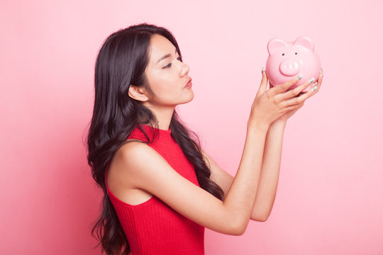 Young Asian woman kiss  a pink coin bank.