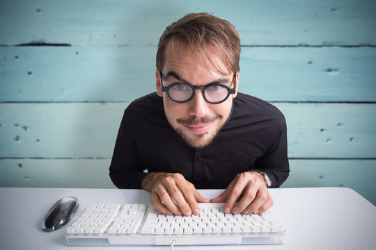 Excited businessman using computer and wearing glasses against painted blue wooden planks
