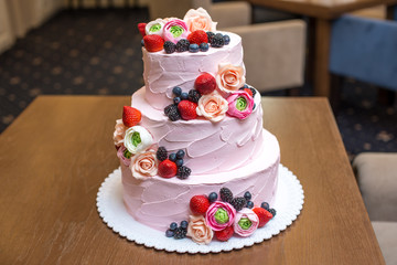 Obraz na płótnie Canvas Three tiered pink wedding cake decorated with berries and flowers. Concept patisserie floristic from sugar mastic