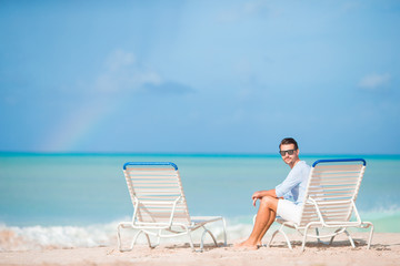 Young man on the beach rest on the chaise-lounge alone