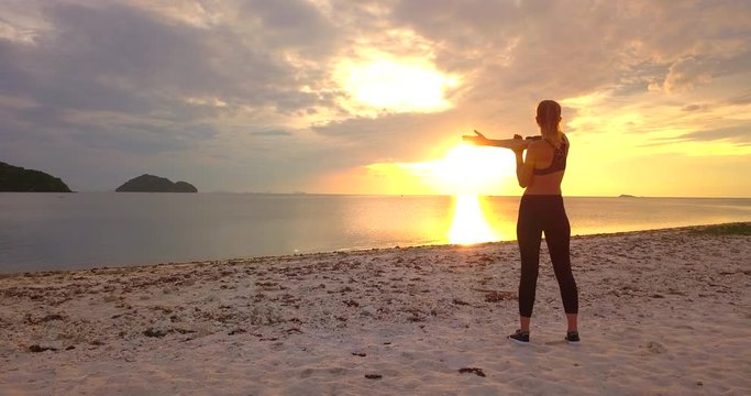 Fitness runner body closeup doing warm-up routine on sand beach at  before running, stretching muscles with standing  stretch. Female athlete preparing  for cardio workout