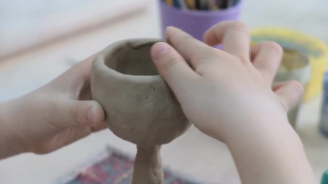 The child learns to mold different kinds of clay products in a ceramic workshop. The child works independently with clay in a lesson in a creative lesson.