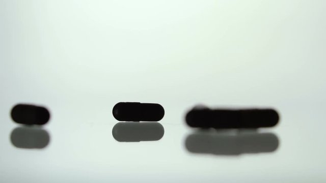 Medical pills scatter on a white background.Black pills. Slow motion. Pills background