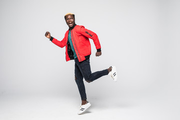 Full length portrait of a happy smiling african man running isolated over gray background