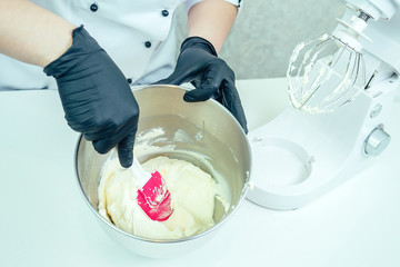 confectioner in black gloves and white work uniforms whipping cream cake cream on the table in a mixer. confectioner, cake, cooking. hands and cake closeup