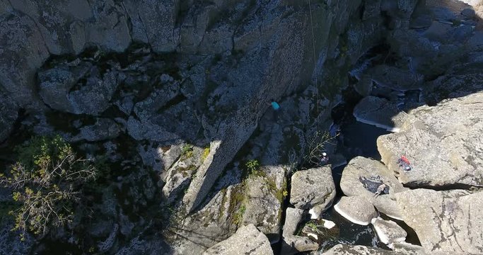 Two mountain climbers prepare an insurance rope at the bottom of a granite rock. Aerial view