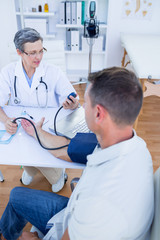 Doctor checking blood pressure of her patient