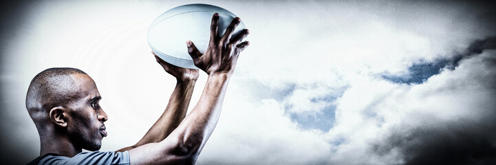 Fototapeta na wymiar Athlete in position of throwing rugby ball against spotlight in sky