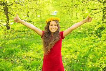 Little girl in red dress and crown of dandelions showing thumbs up symbol.