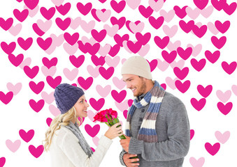 Attractive man in winter fashion offering roses to girlfriend against valentines day pattern